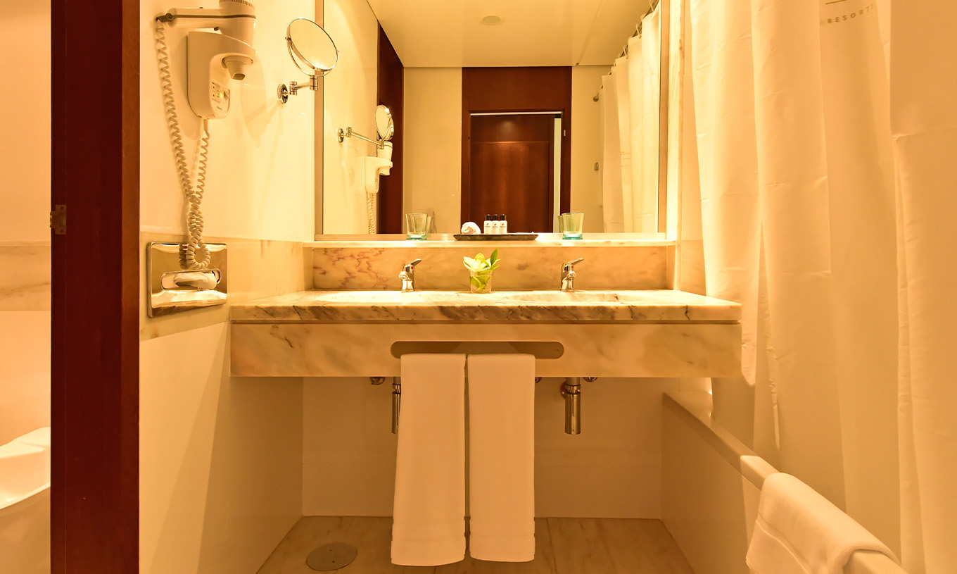 The Sea View Suite at Pestana Casino Park has a bathroom with a marble sink, bathtub, and hairdryer