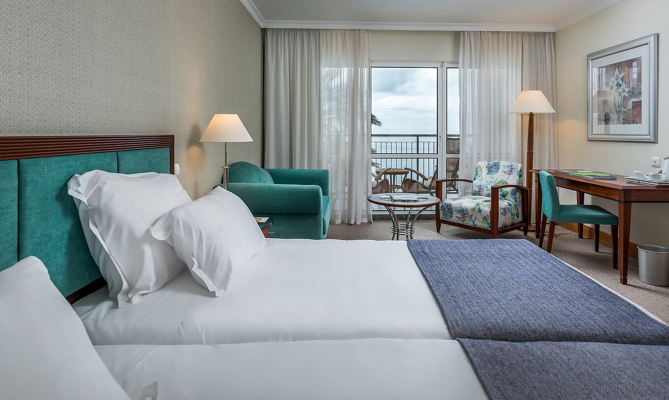 The Classic Sea View Room at Pestana Grand has two single beds, an armchair and a balcony