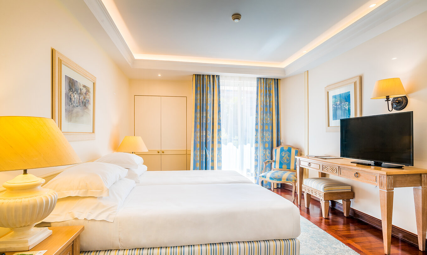 The Classic Room of Pestana Royal All Inclusive has two single beds, bedside table with lamp, and television