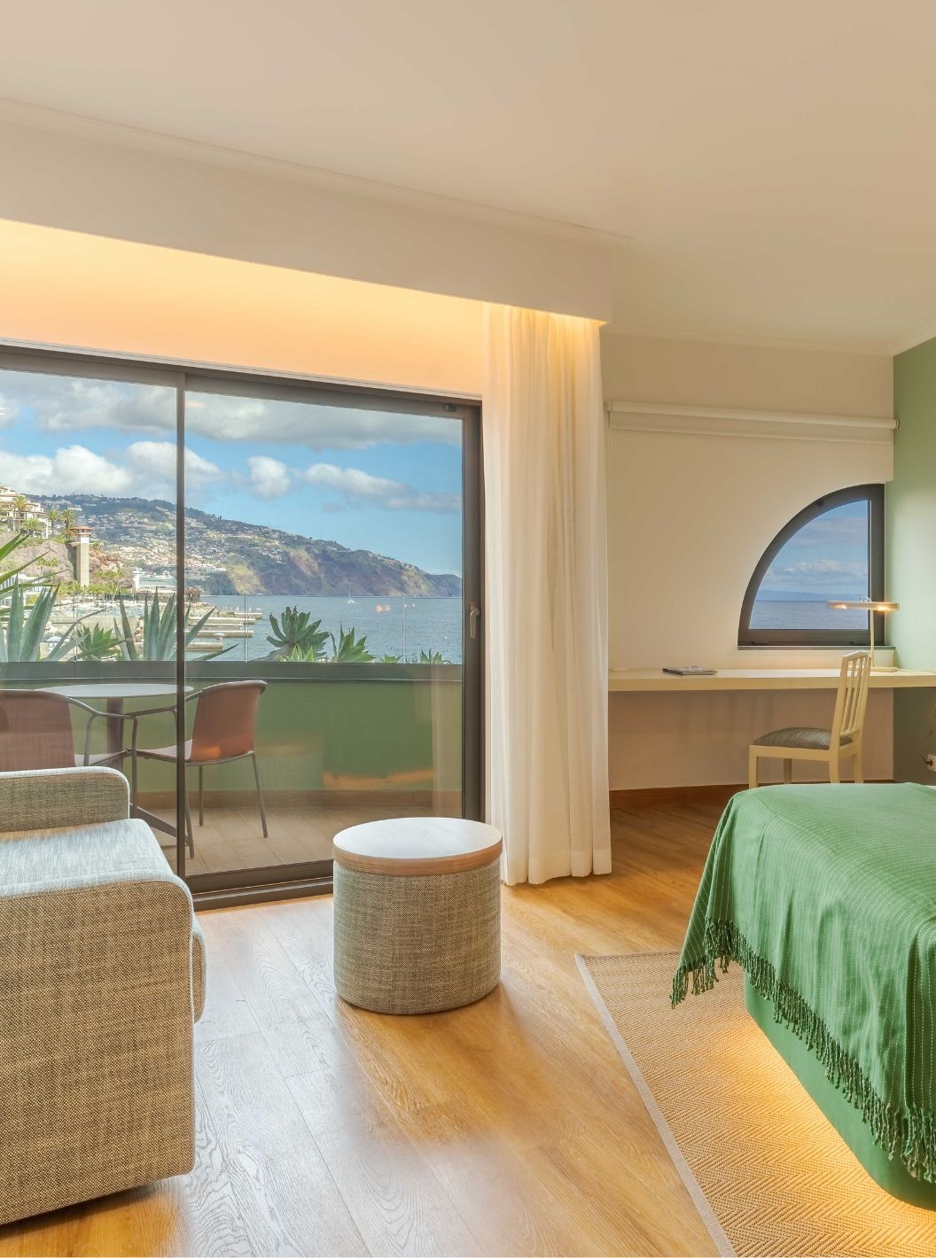 The Superior Side Sea View at the Pestana Vila Lido Madeira has a large window leading out onto the balcony, a desk and a sofa