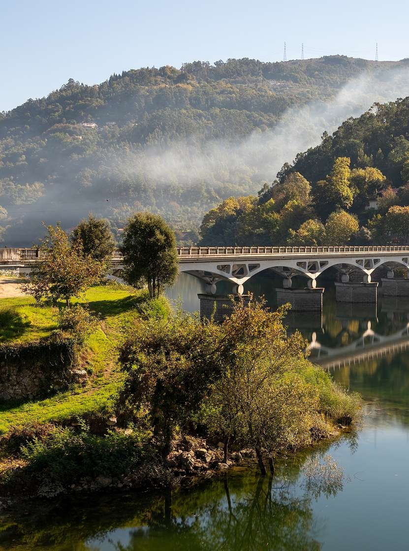 Landscape of northern Portugal with a stone bridge over a river, surrounded by green hills