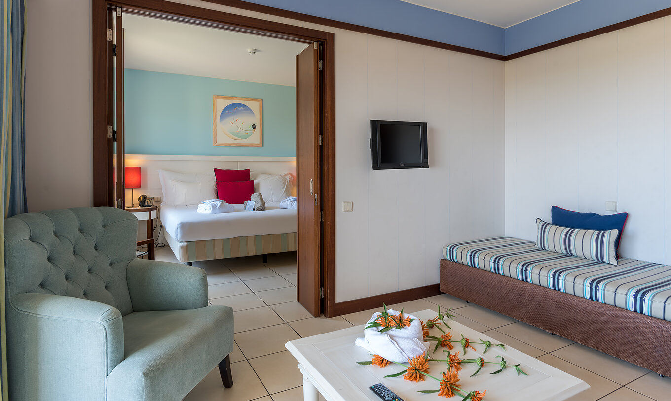 The T1 Suite Apartment of Pestana Porto Santo All Inclusive has a bedroom with a double bed and a living room with a sofa
