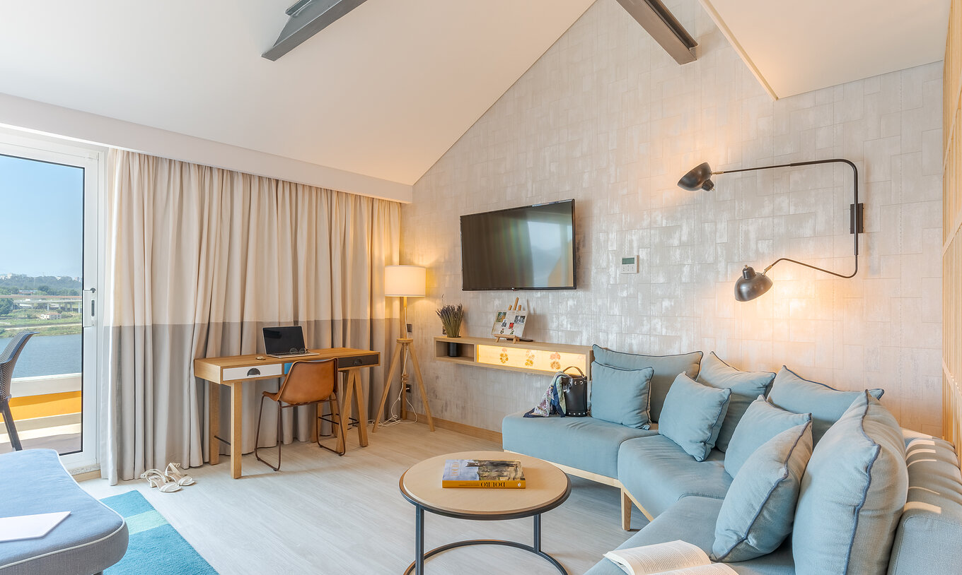 The Junior Suite at Pestana Douro Riverside features a television, a desk with a table, and a sofa