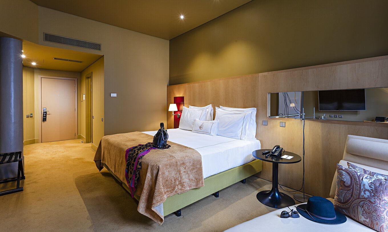 Pestana Palácio do Freixo’s Classic room has yellow walls, a double bed, and a beige sofa bed