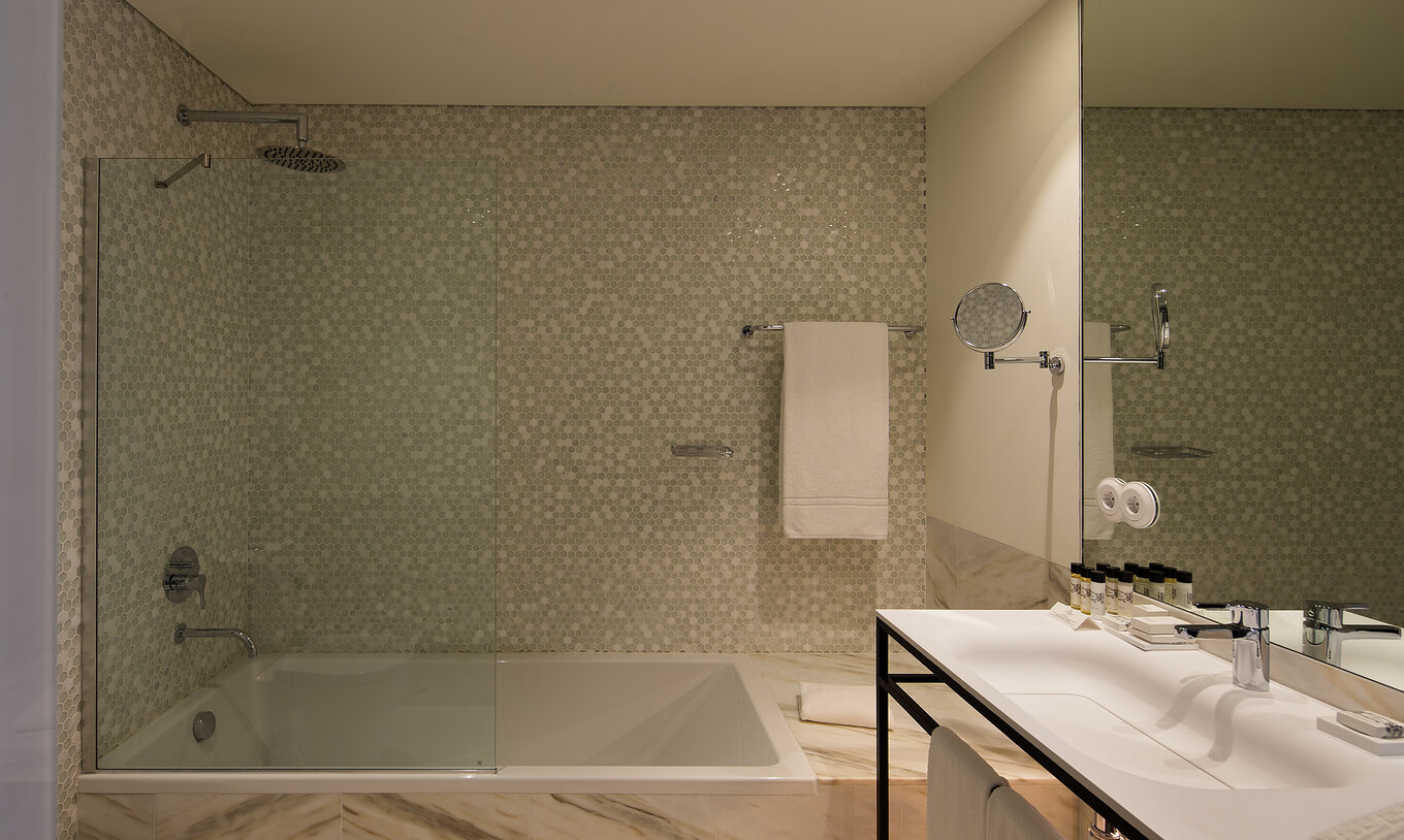 The Deluxe Executive Grand View do Pestana Porto - A Brasileira has a large bathtub with shower with hexagonal tiles