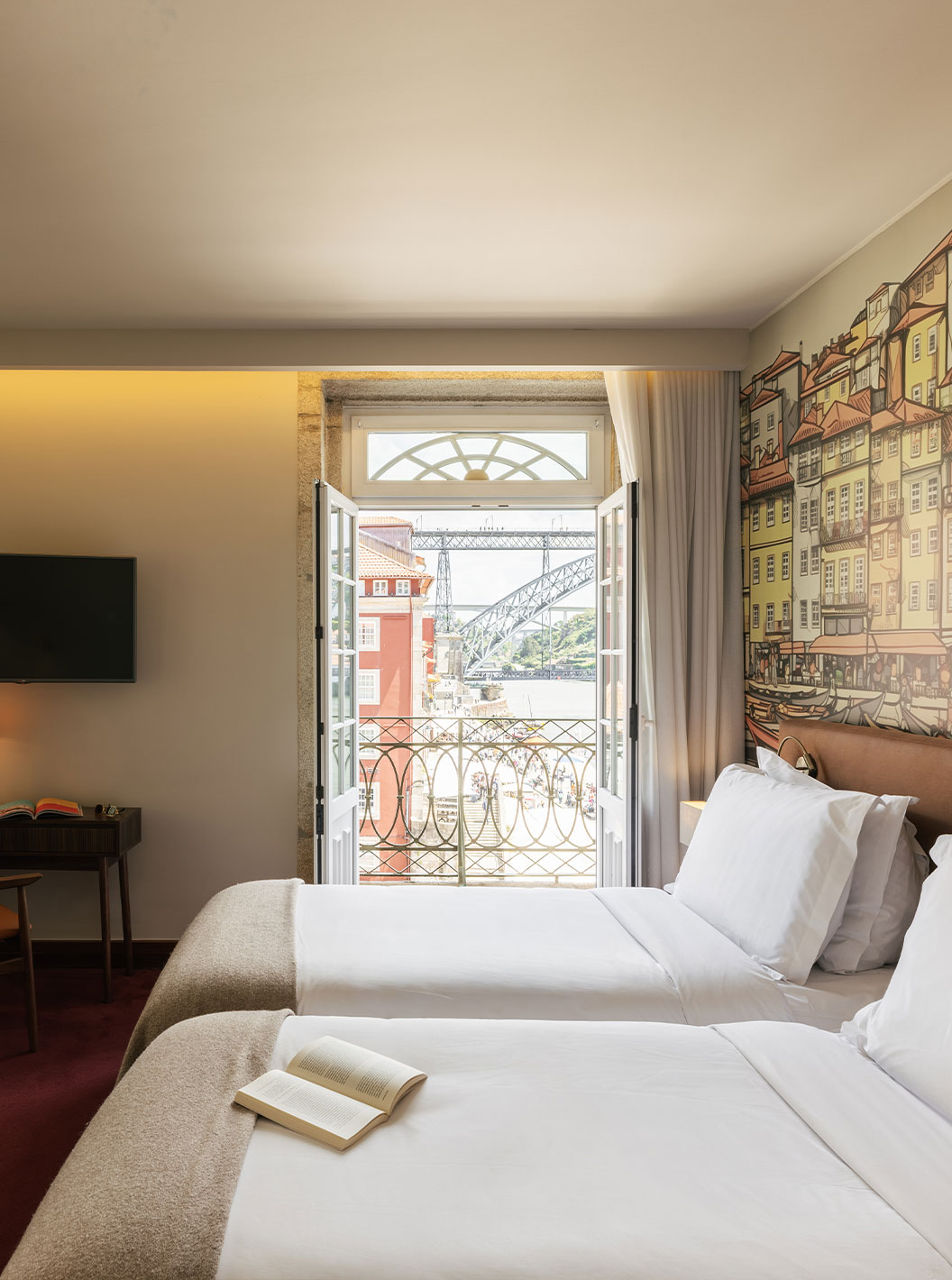 Plaza room at Pestana Vintage Porto featuring twin beds, mural wall art and balcony views of the bridge