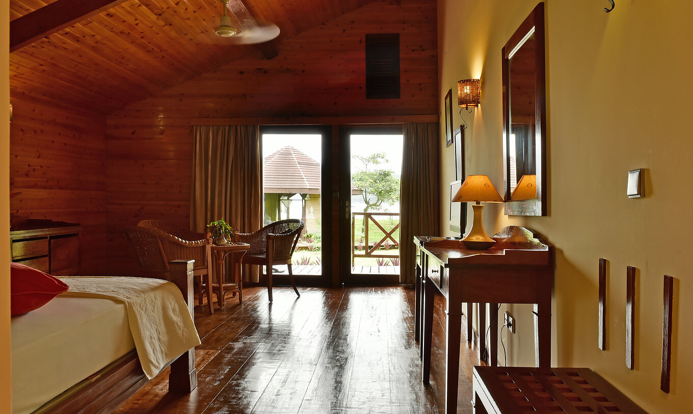 The Superior Double at Pestana Equador Ilheu das Rolas includes a wooden dresser, a mirror, and a window with a garden view