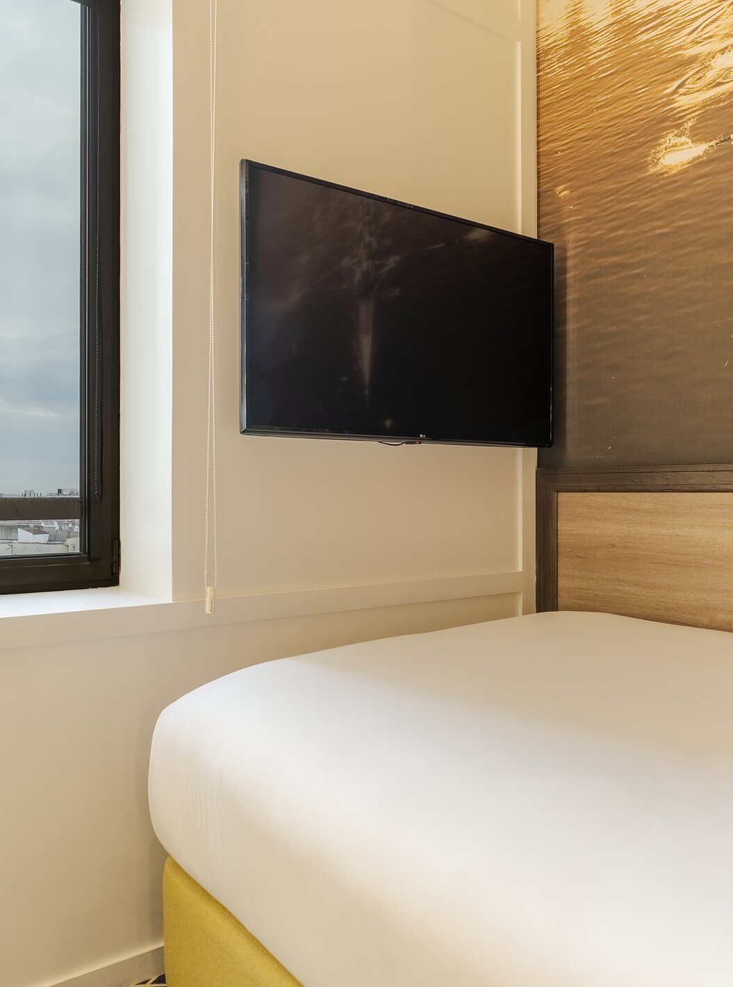 Cozy Room at Pestana CR7 Gran Vía Madrid with wall mounted television beside a bed and bright window