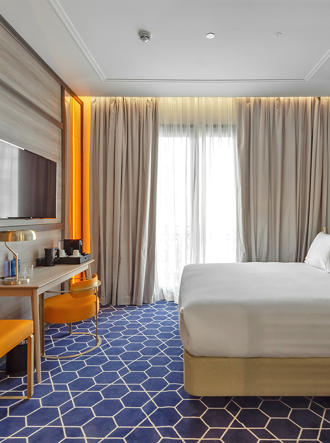 The Premium Room at Pestana CR7 Gran Vía Madrid includes a double bed, desk, chair, television, and curtained window