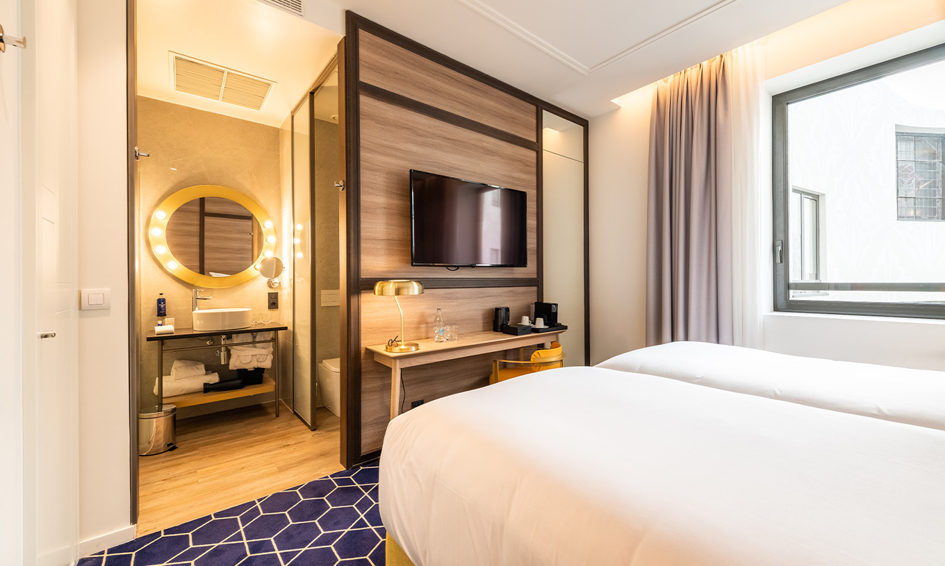The Superior Room at Pestana CR7 Gran Vía Madrid includes two beds, a round mirror, and a window facing the courtyard