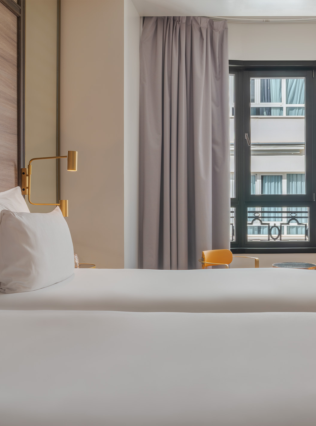 The Legend Room at Pestana CR7 Gran Vía Madrid with white bedding beside tall curtains and a city view