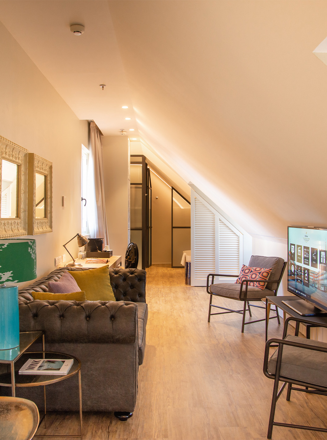 The Suite Plaza Mayor at Pestana Plaza Mayor Madrid has a living room with sofa, chairs, TV and paintings on the wall