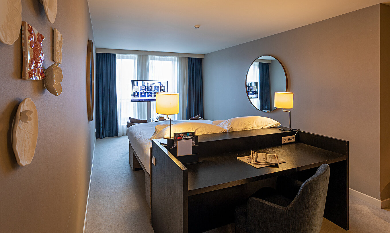 Executive - River View room at Pestana Amsterdam Riverside has a TV in front of the bed and a desk