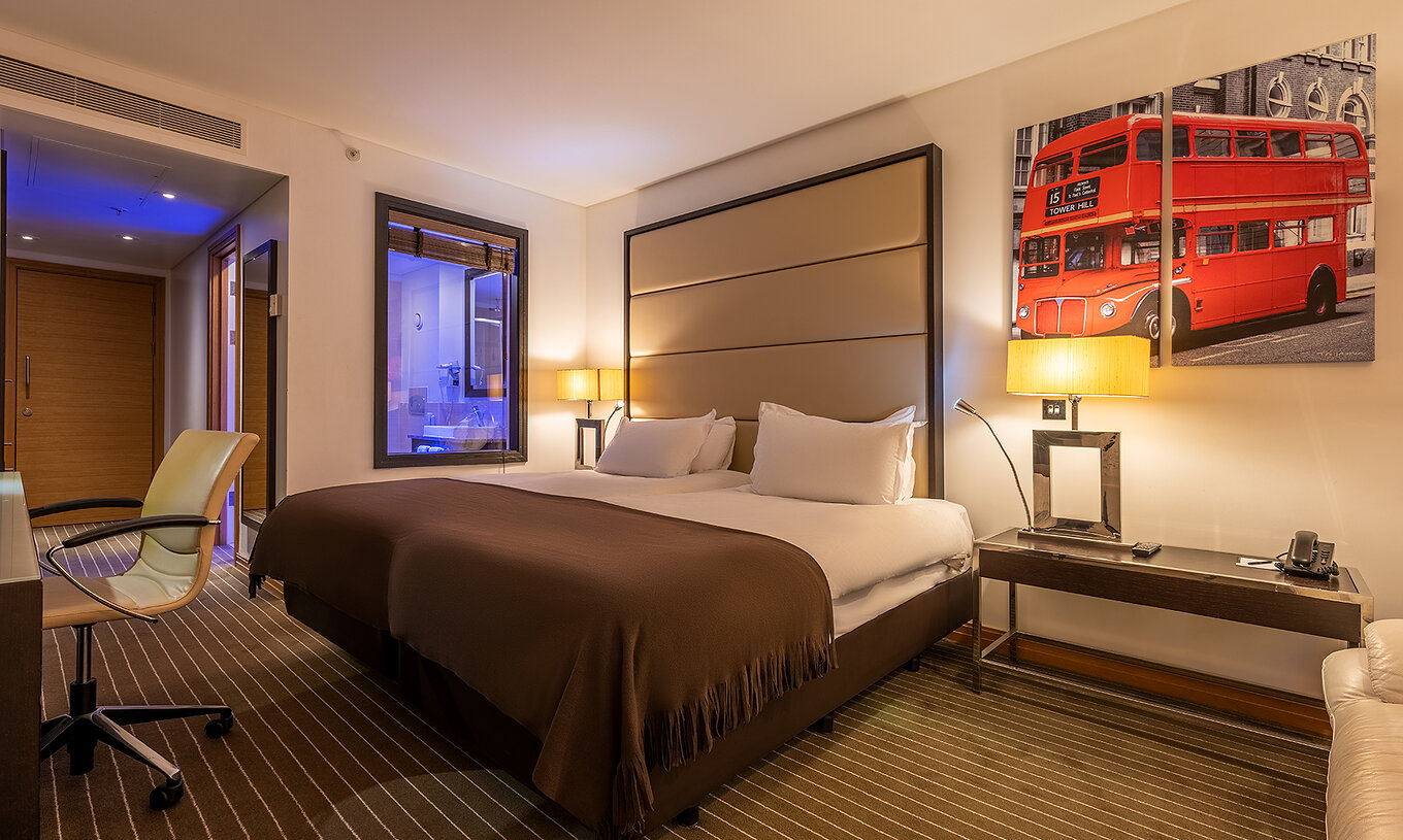 The Premium Twin at Pestana Chelsea Bridge has two beds, London wall art, nightstand, sofa and a chair