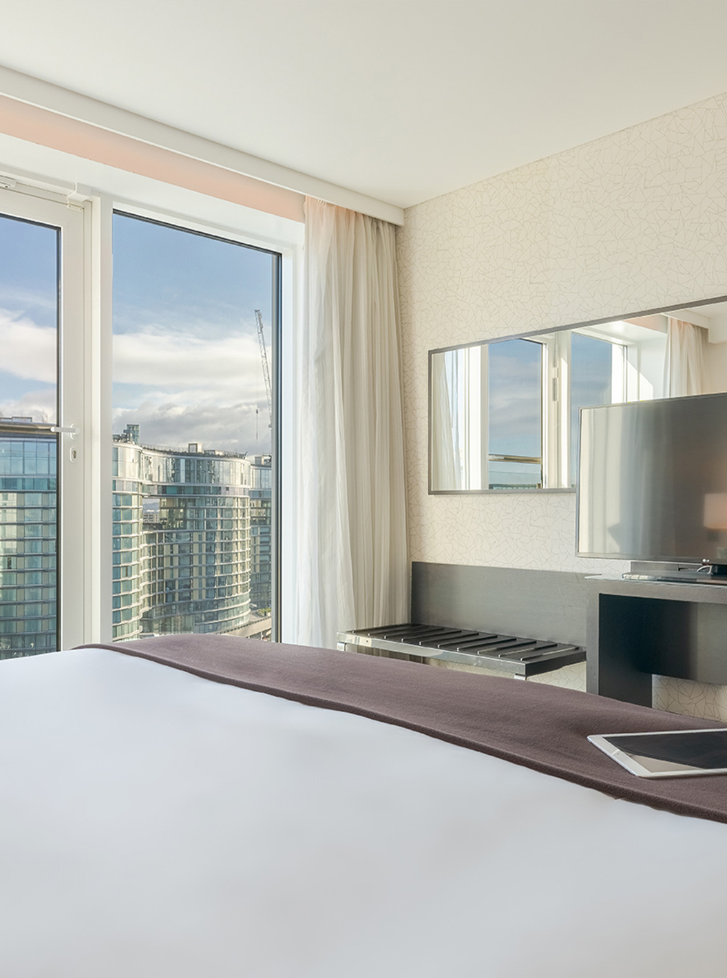 The Superior King at Pestana Chelsea Bridge has double bed, desk with TV, sofa and windows facing the city