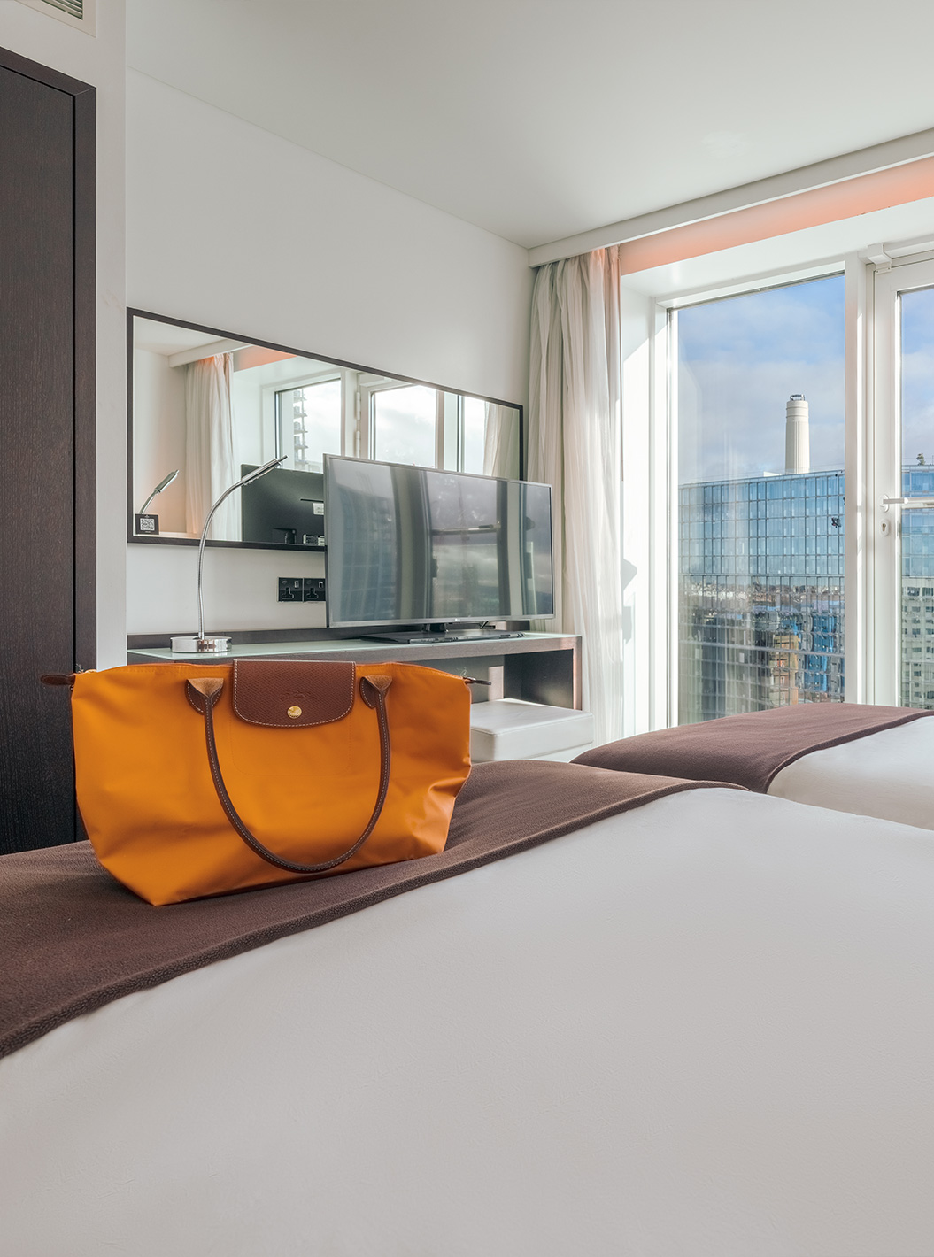 The Superior Twin at Pestana Chelsea Bridge has two beds, TV, mirror, city view window and curtains