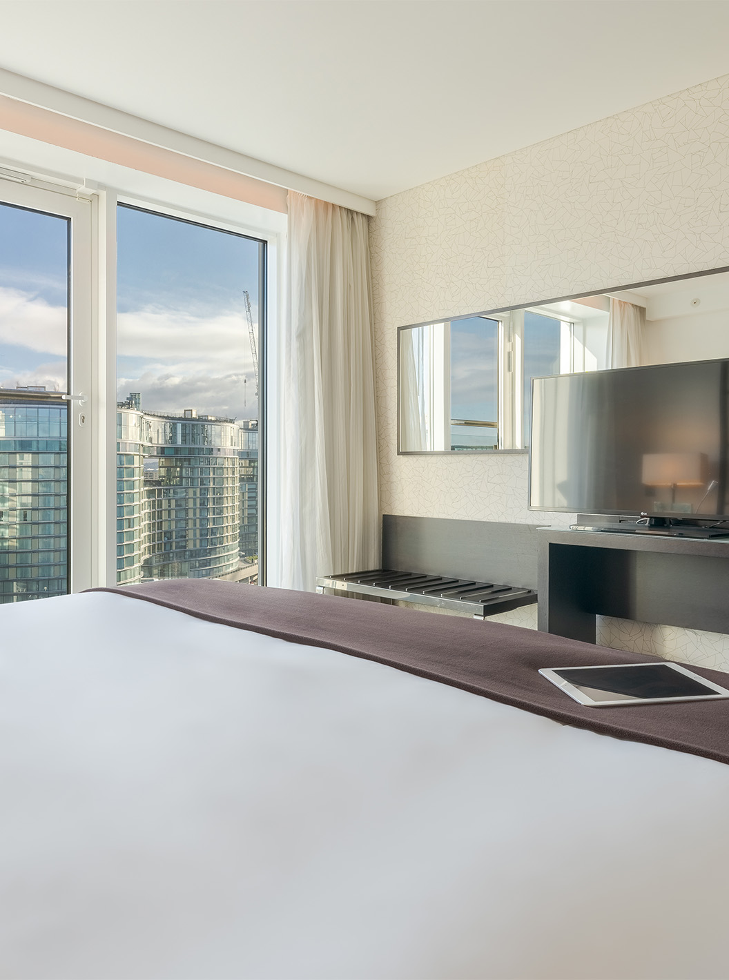 The Signature Suite with 2 Bedrooms at Pestana Chelsea Bridge has a double bed, a desk with a TV, and city windows