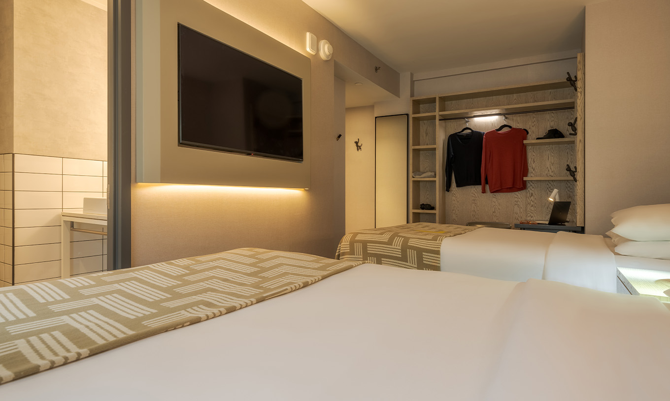 The Superior Double at Pestana CR7 Times Square has two beds with a bedspread with the number seven, a TV, and a wardrobe