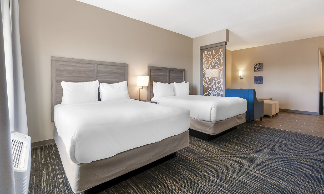 The Master Double Queen Suite at Pestana Orlando Suites Lake Buena Vista has two beds and a bedside table with a lamp