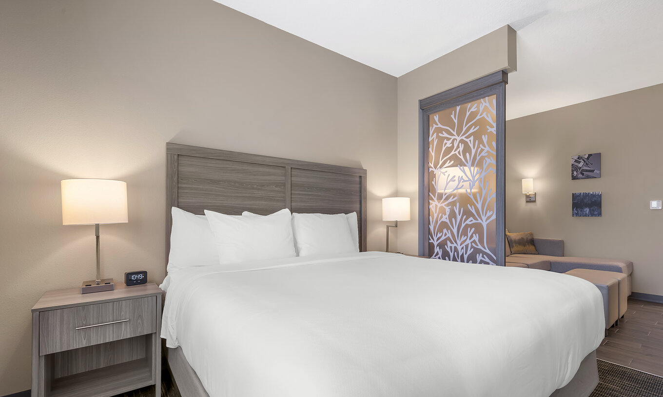 The King Master Suite at Pestana Orlando Suites Lake Buena Vista has a double bed and a bedside table with a lamp
