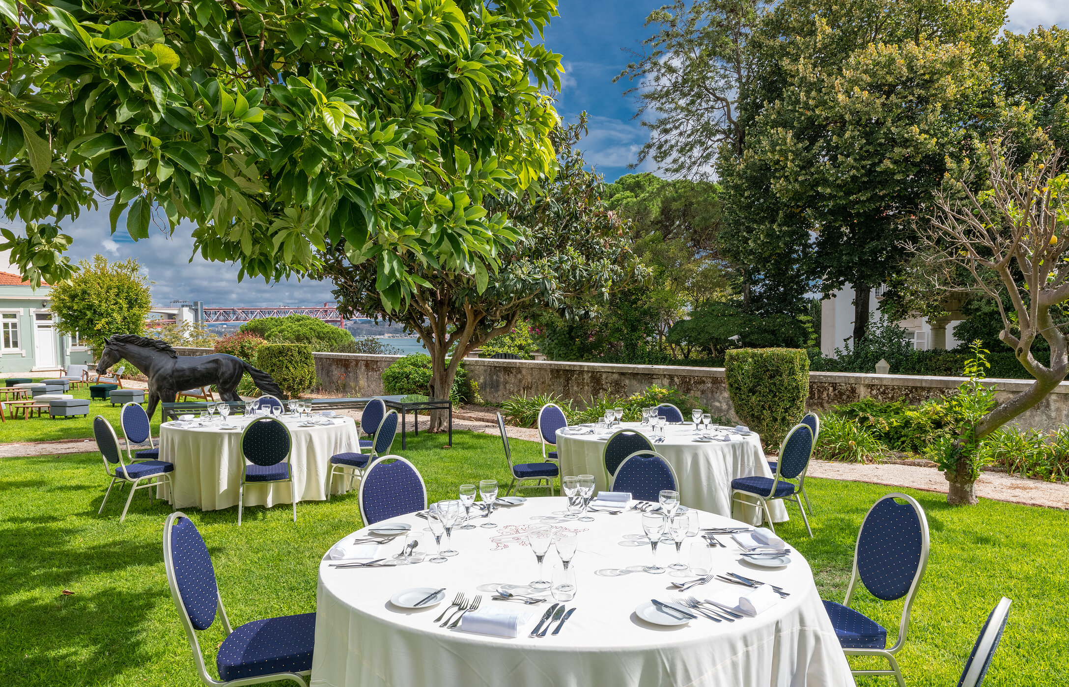 Wedding in an elegant and sophisticated outdoor space, with round tables on well-kept grass and a view of the Tagus River