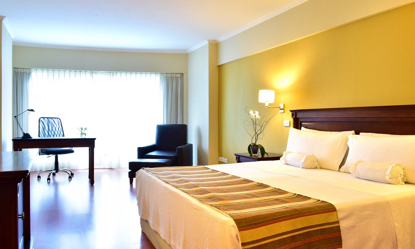 The Queen Superior Room at Pestana Buenos Aires has a double bed, a bedside table, a desk, and a chair