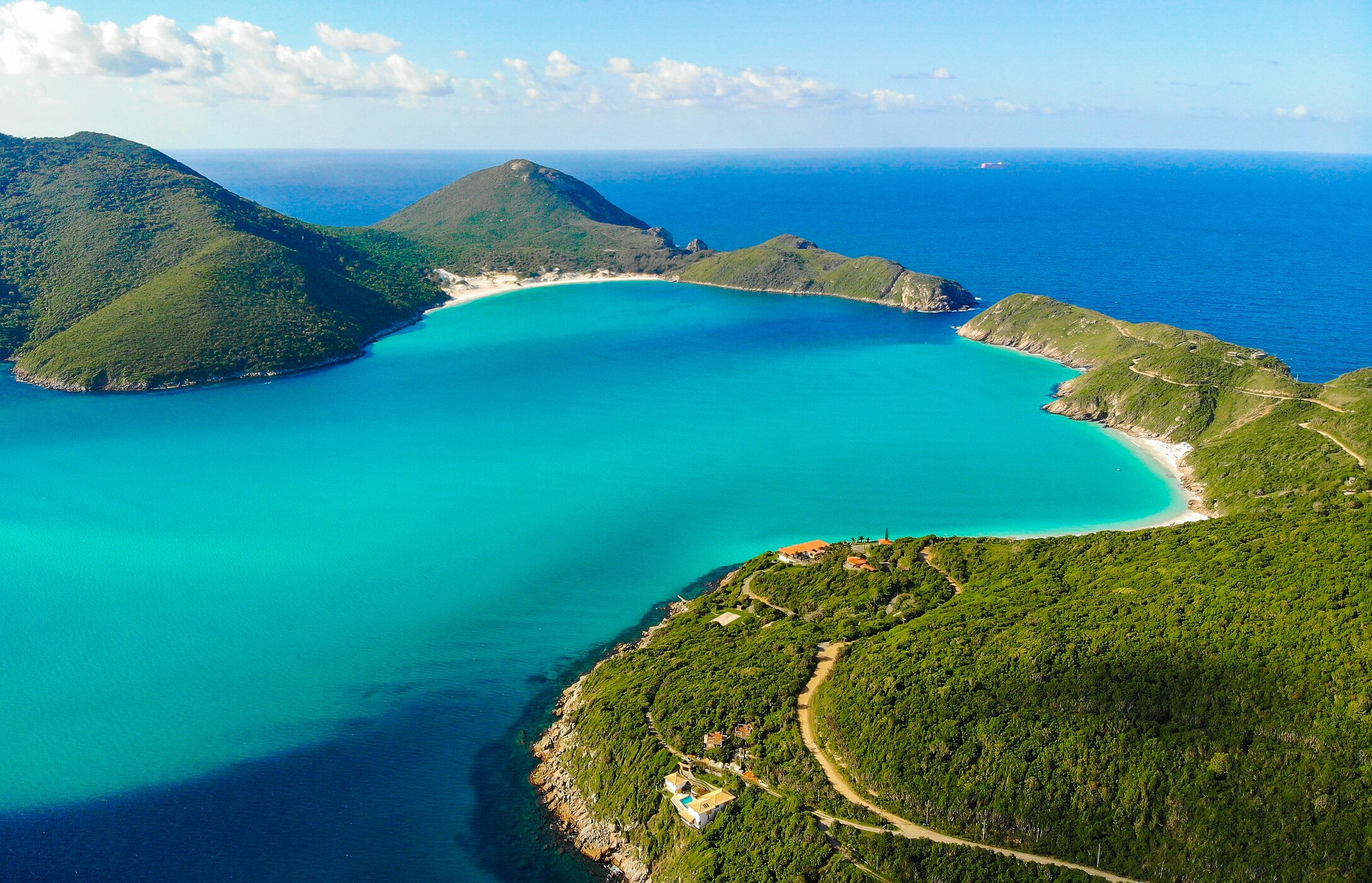 Aerial view of Cabo beach, with crystal-clear waters and surrounded by vegetated mountains, in Rio de Janeiro, Brazil