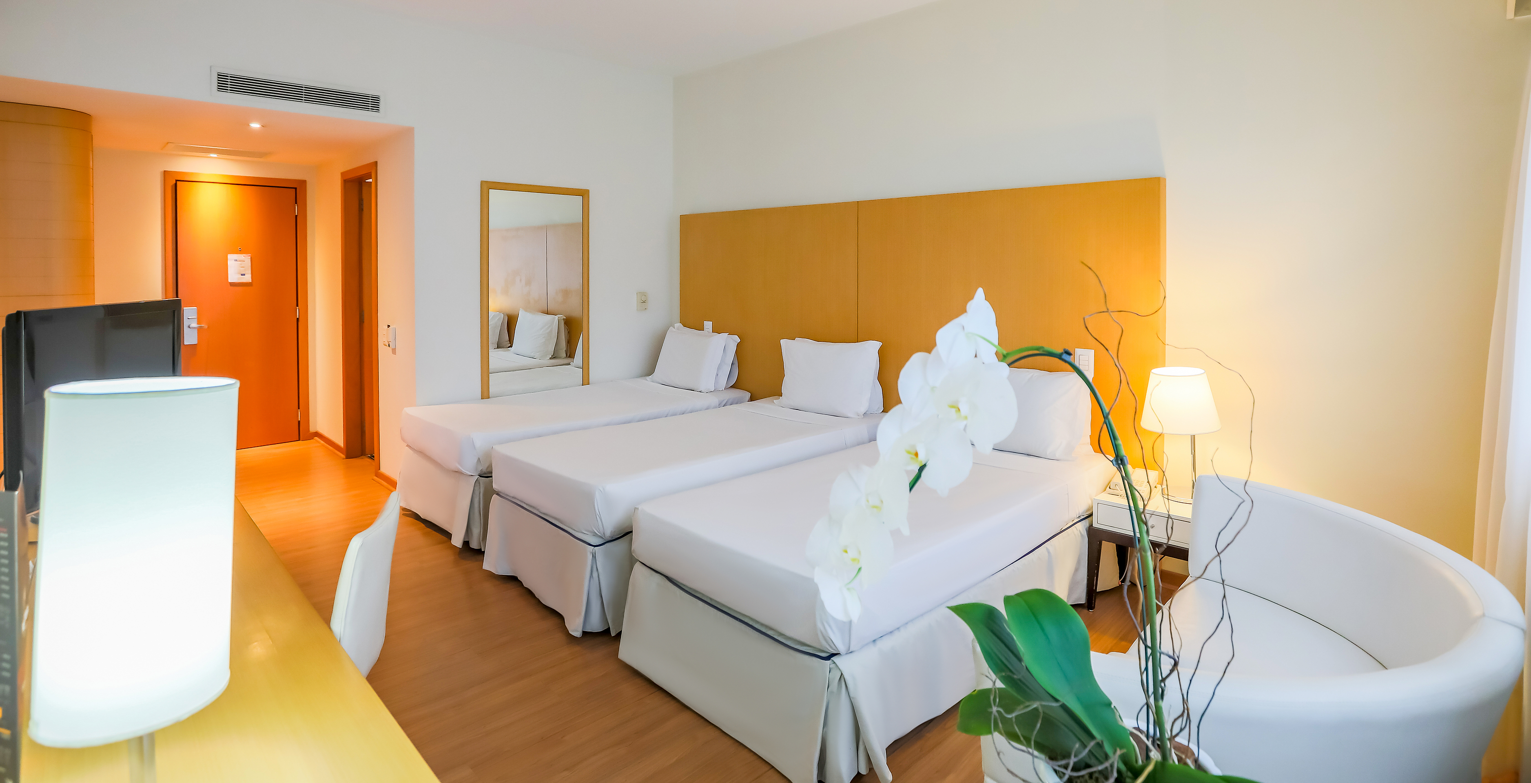 The Twin Luxury Corner at Pestana Curitiba has three single beds with a desk, television, and a small sofa