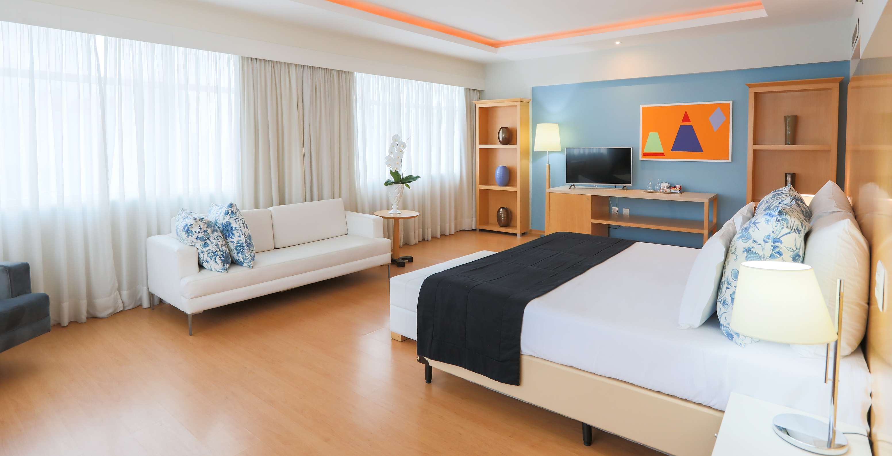 The Executive Suite at Pestana Curitiba is a spacious room with several windows, very bright, with a double bed and sofa