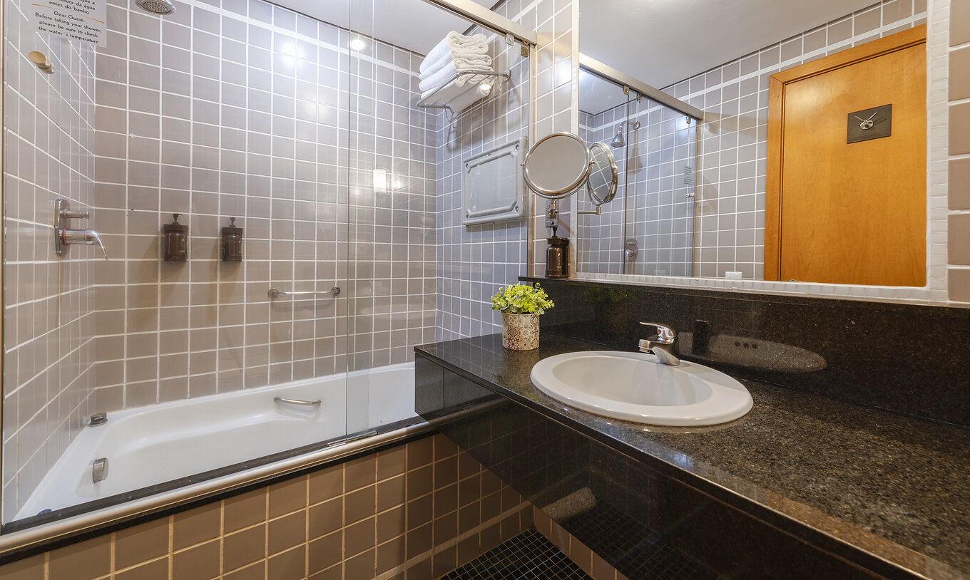 The Twin Superior at Pestana Curitiba has a bathroom with a bathtub in gray tiles and a countertop with a sink