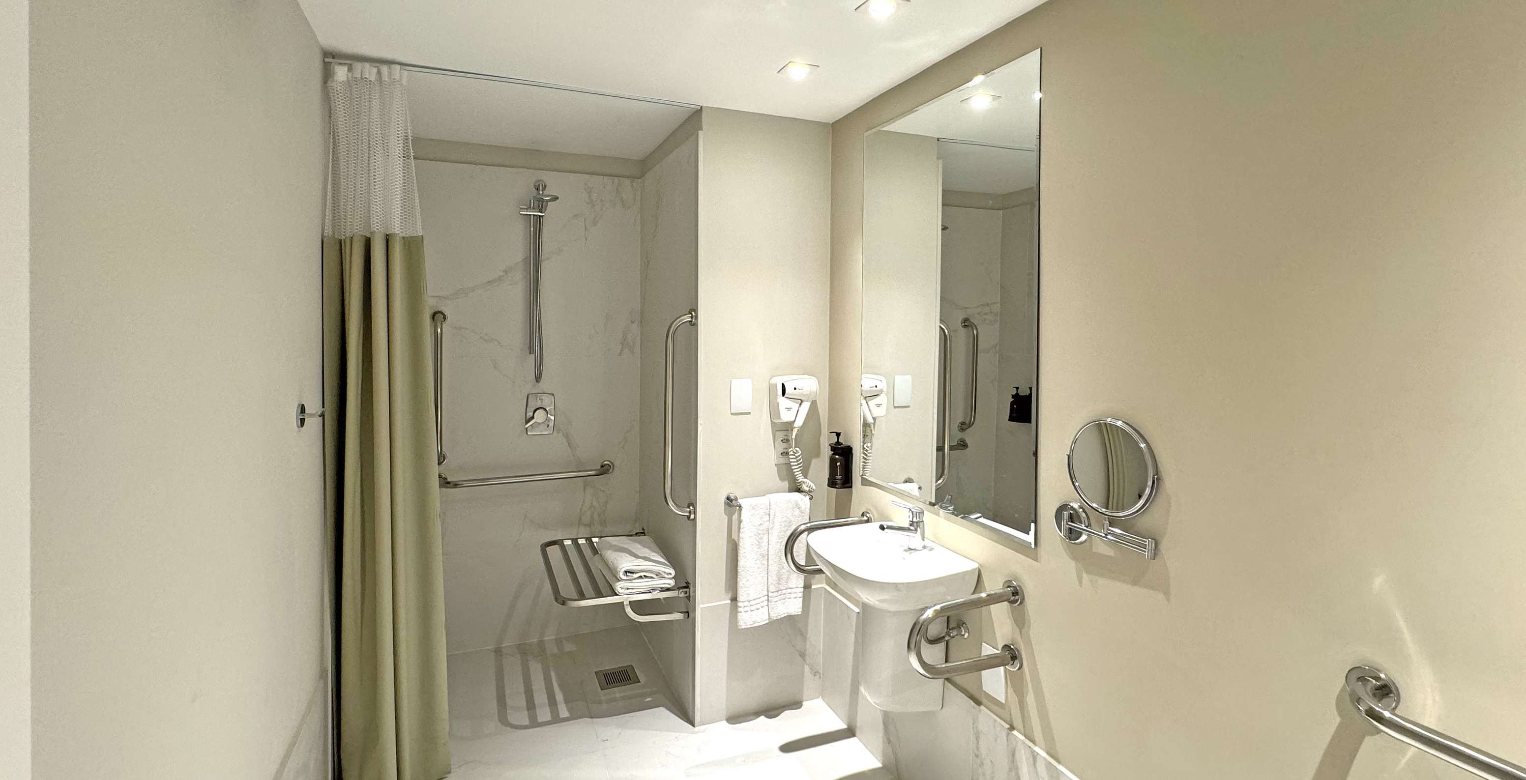 The Queen Disable Standard of Pestana Rio Atlântica has an adapted bathroom with shower, sink, mirror, and hairdryer