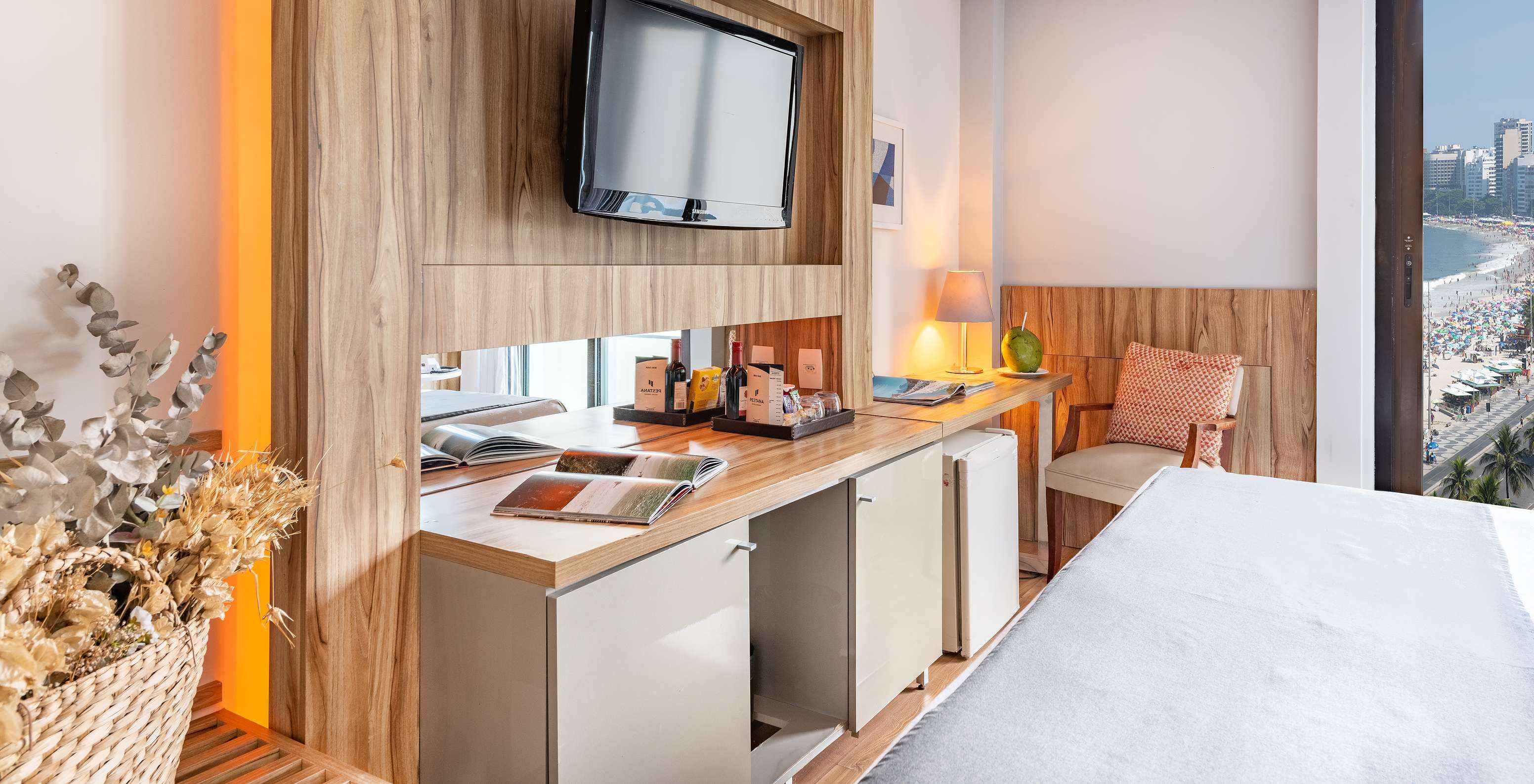 The Queen Side Sea View of Pestana Rio Atlântica has a television in front of the bed and a cushioned chair