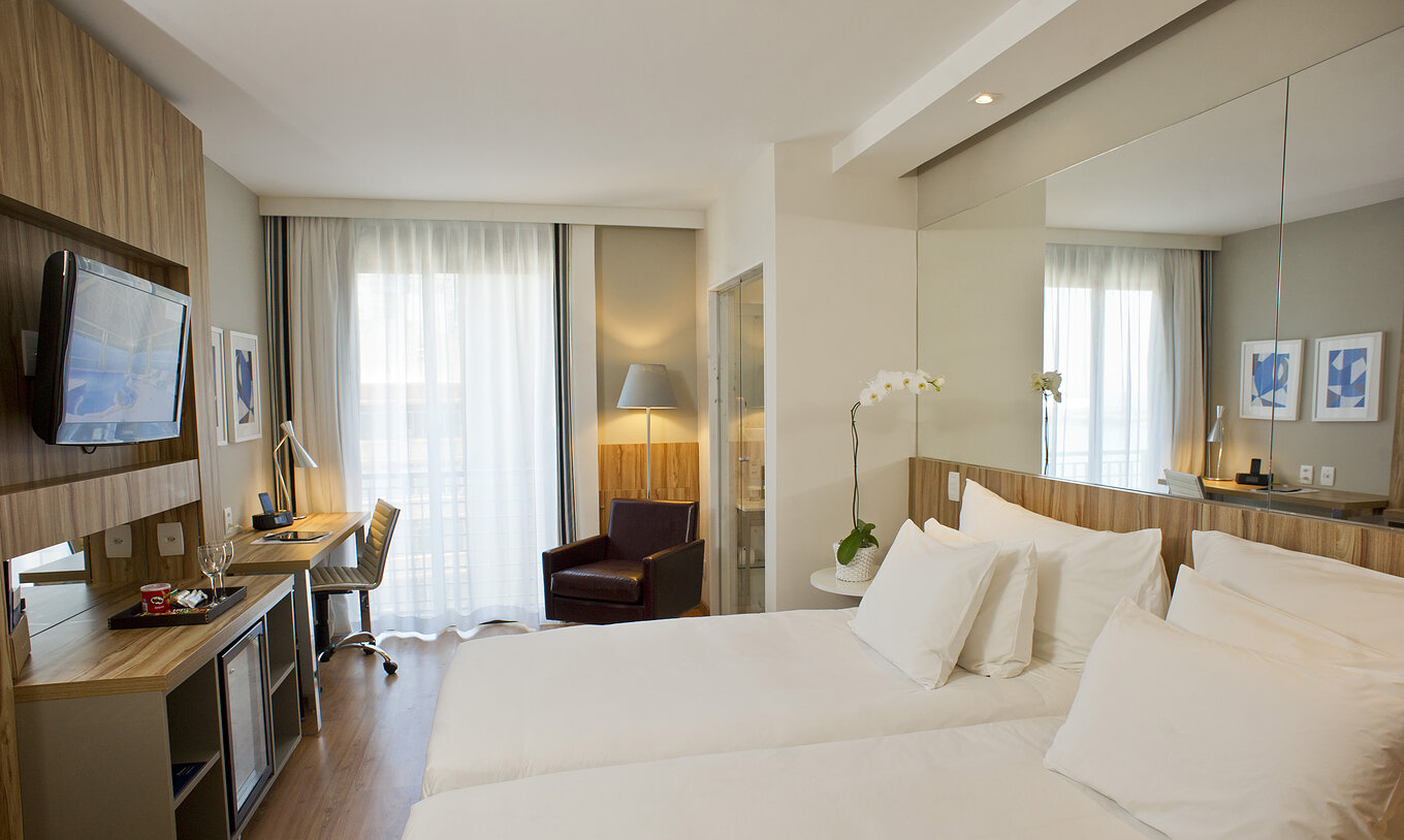 The Lateral Sea View Twin Room of Pestana Rio Atlântica has two beds with a mirror on the headboard and a television in front