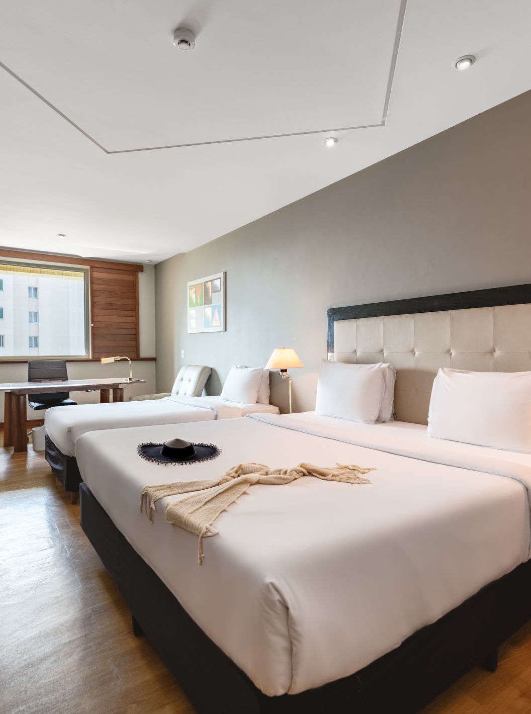 The Family Room at Pestana São Paulo has a double bed, two bedside tables, a desk, and a window