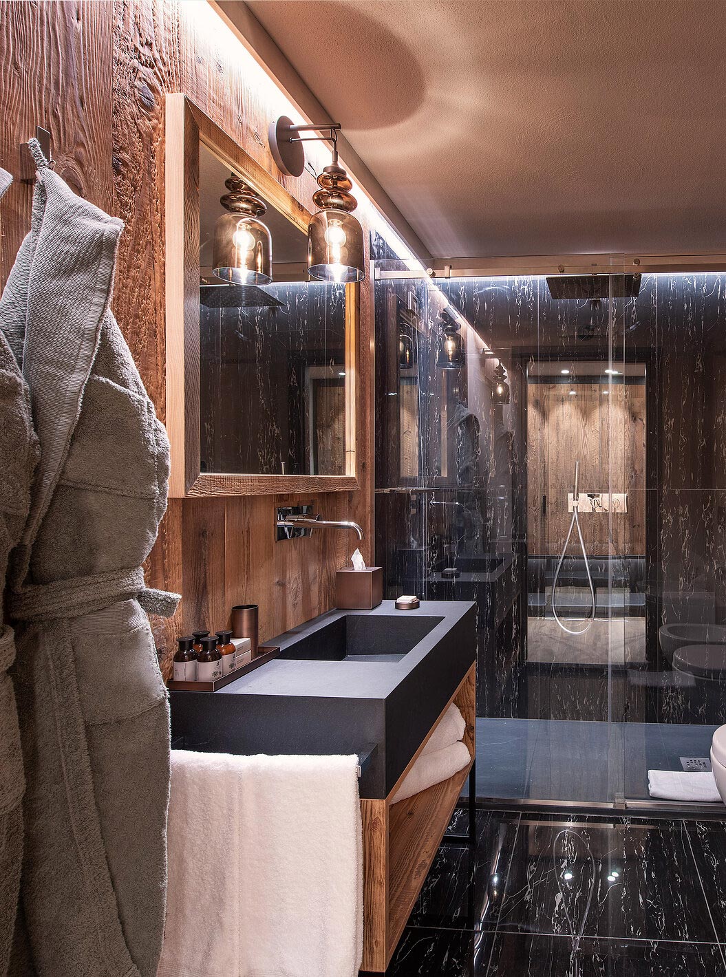 Junior Suite at Le Massif Courmayeur featuring a dark marble shower, wood vanity and glass bathroom lighting