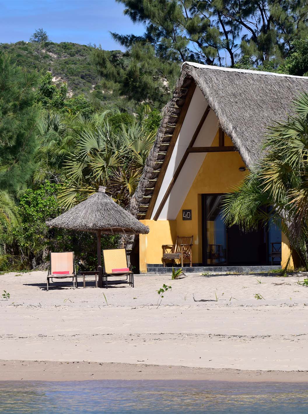 Bungalow Suite T2 at Pestana Bazaruto Lodge is a small house with a thatched roof on the beach, surrounded by greenery