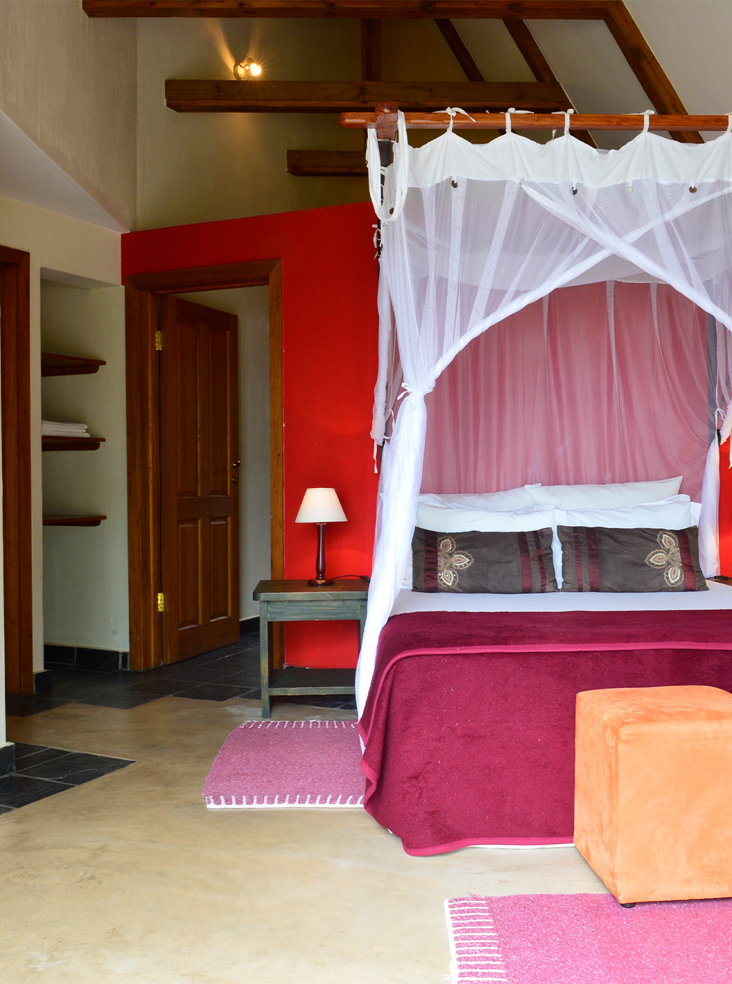 Bungalow T1 at Pestana Bazaruto Lodge has decor in red tones with a double bed, sofa and desk