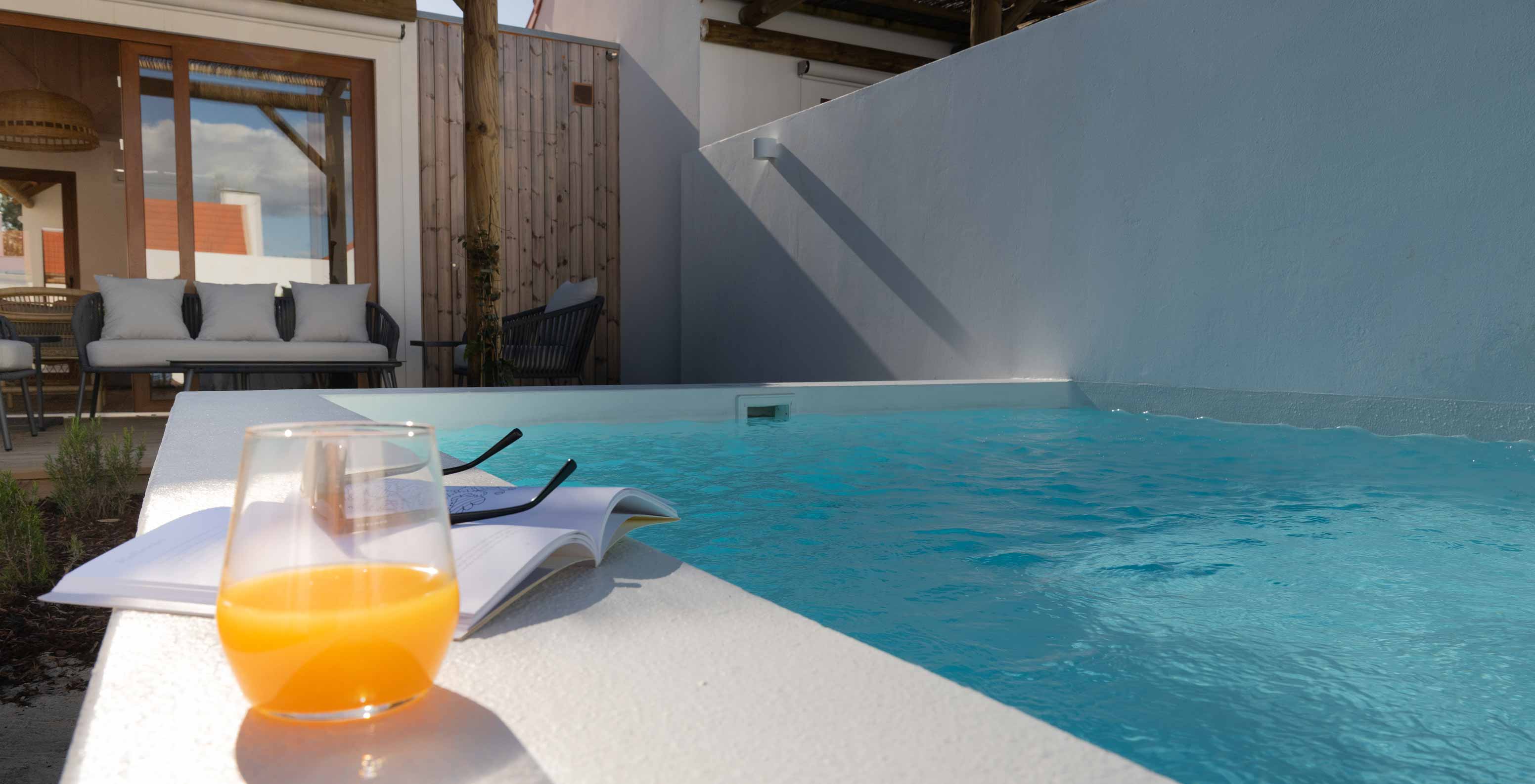 The Superior Green Villa at Pestana Comporta Village Residences has a patio with a glass of juice and a book near the pool
