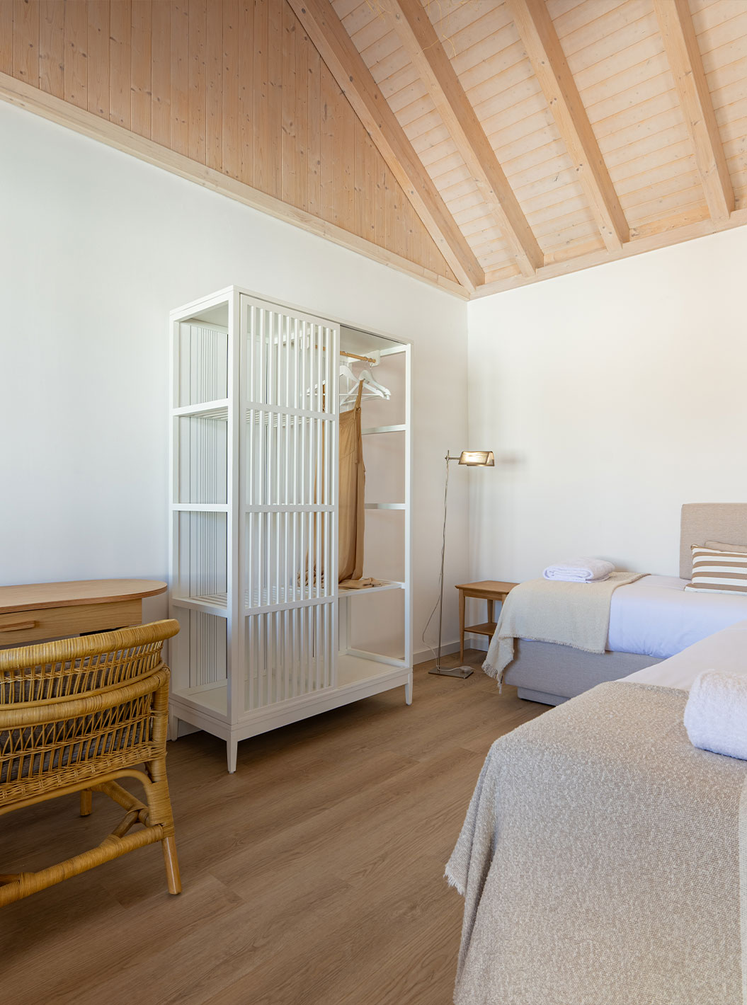 The Standard Villa at Pestana Comporta Village Residences has a bedroom with a bed, a table, and a wicker chair