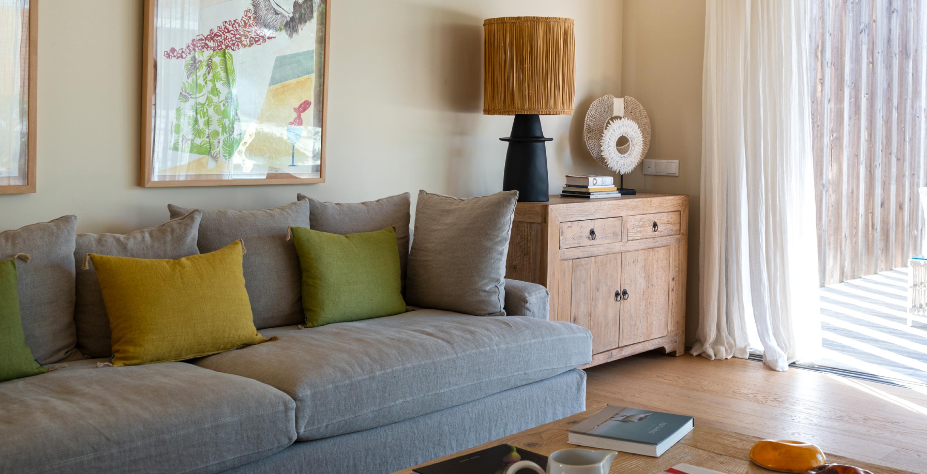 The exclusive villa with a pool at Pestana Tróia Eco Resort has a living room with a gray sofa and large window with curtains