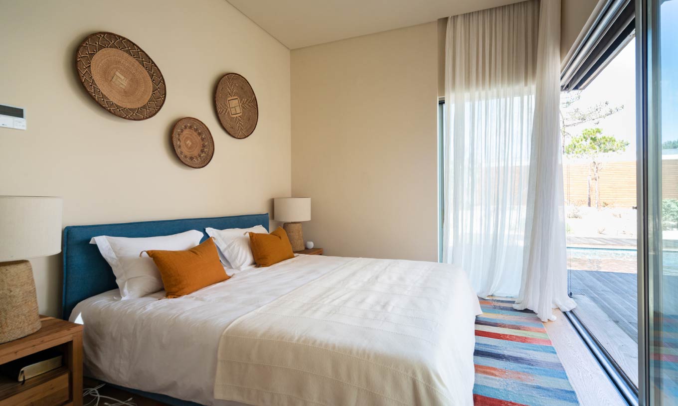 The exclusive villa with a pool at Pestana Tróia Eco Resort has a double bed with orange cushions in front of a window