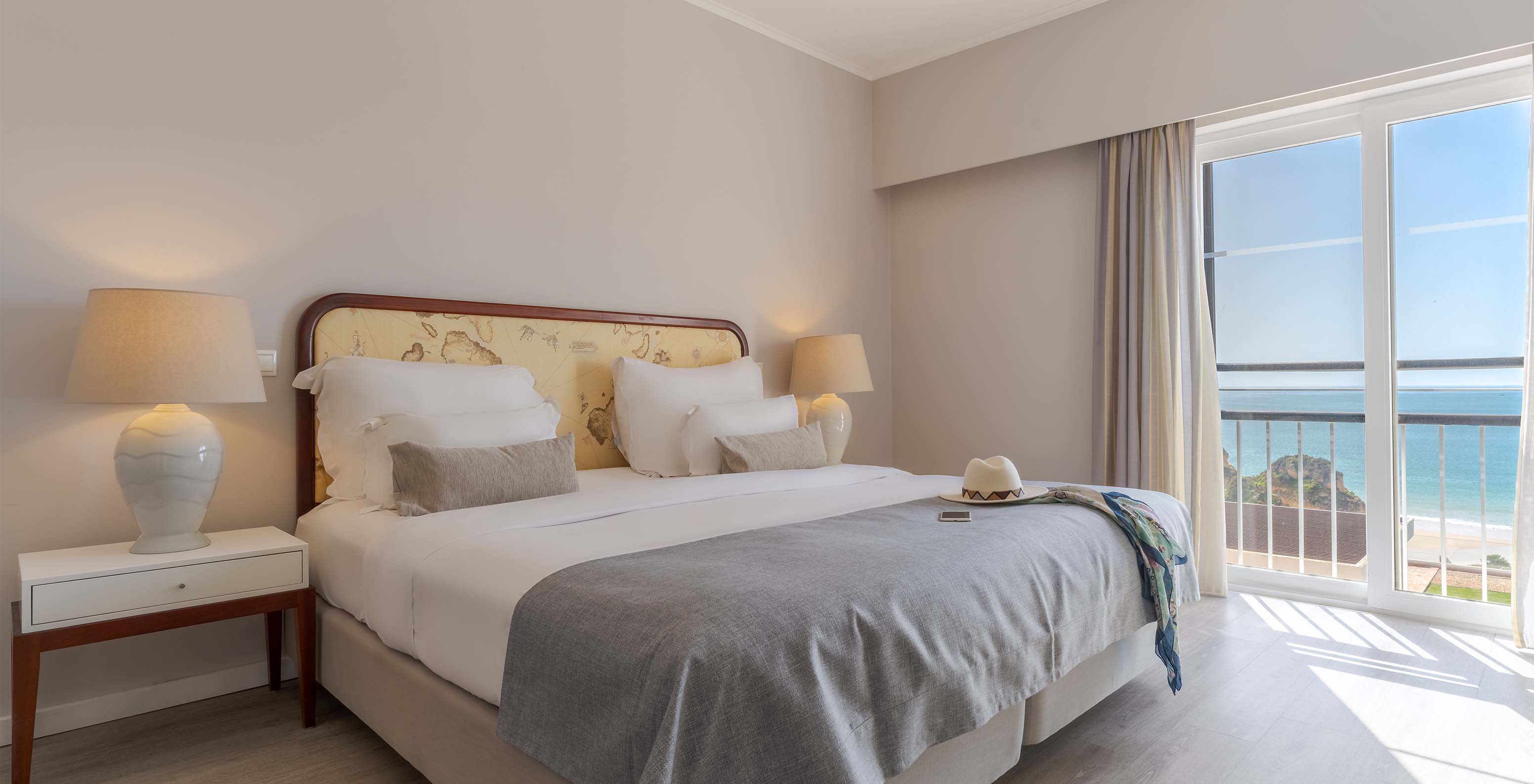 The Luxury Sea View Suite at Pestana Alvor Praia has a double bed, a bedside table with lamp, and sea views