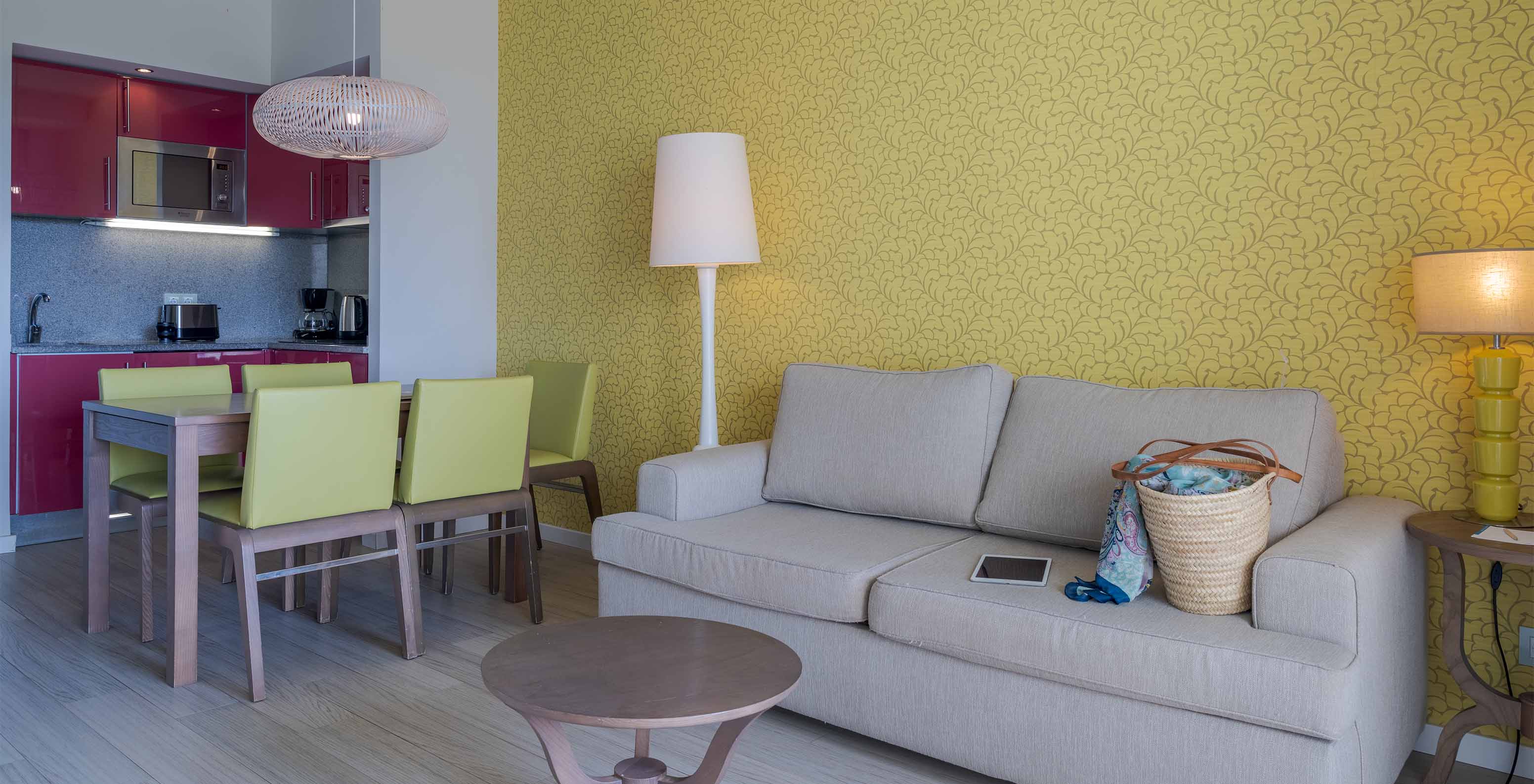 The Garden View Suite T1 at Pestana Alvor Praia has a dining table with five green chairs and a sofa