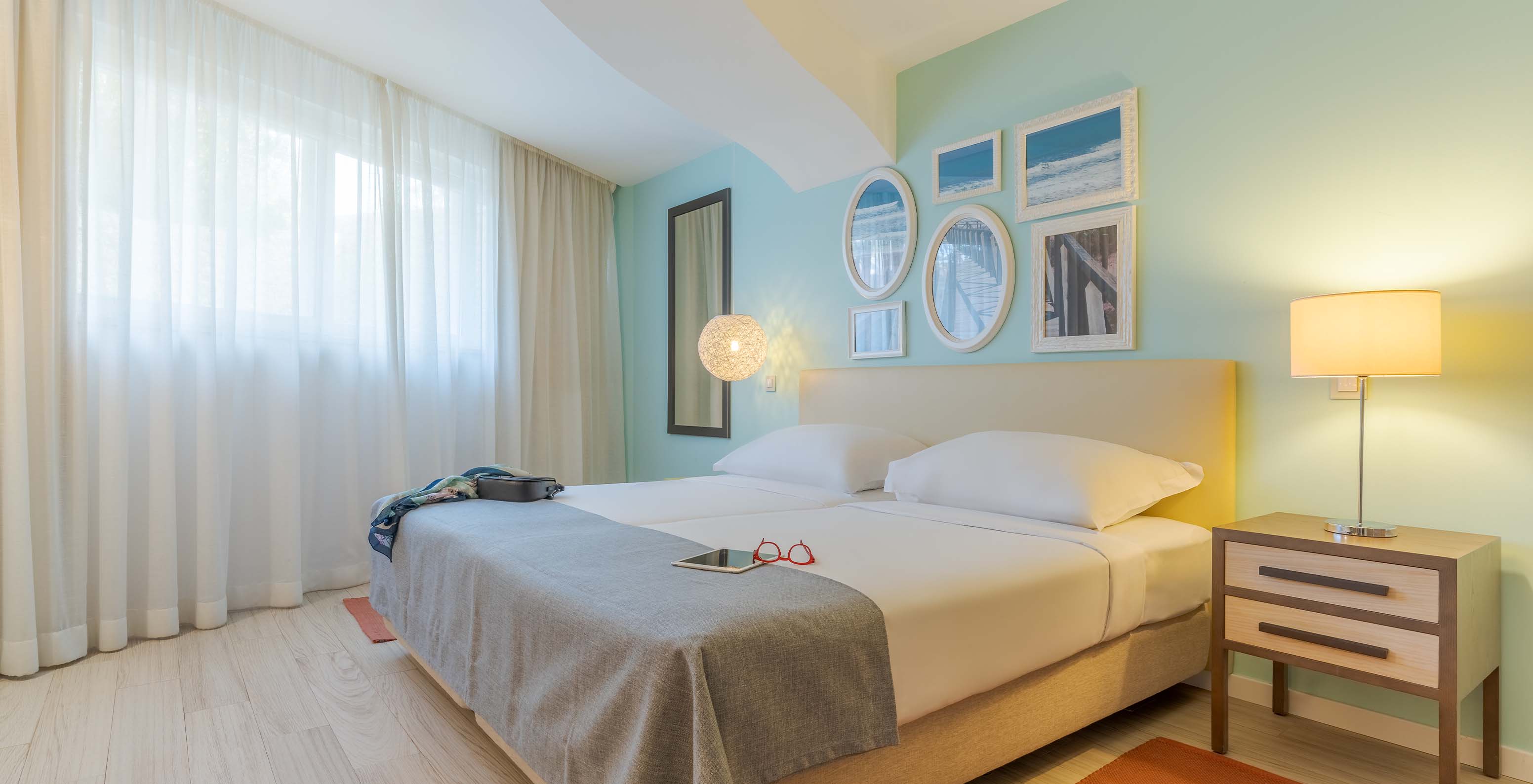 The Duplex Sea View Suite T1 at Pestana Alvor Praia has two joined beds, a bedside table, rug, and art