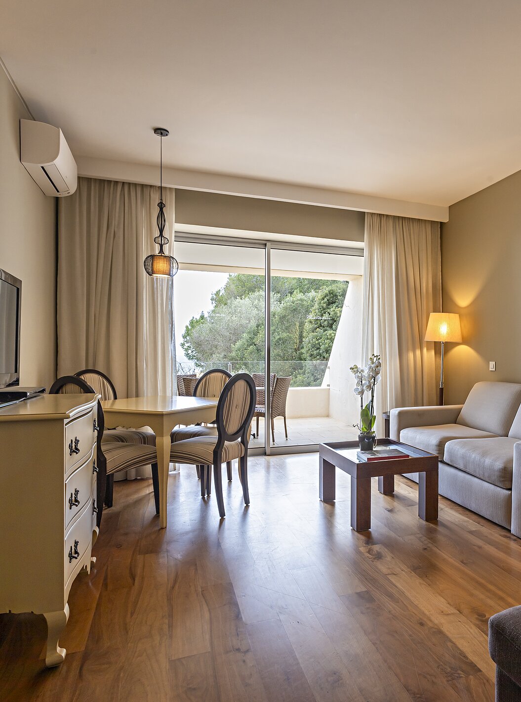 The Cliff Suite T1 at Pestana Alvor Praia has a living room with two sofas, a dresser with a TV, a dining table, and chairs