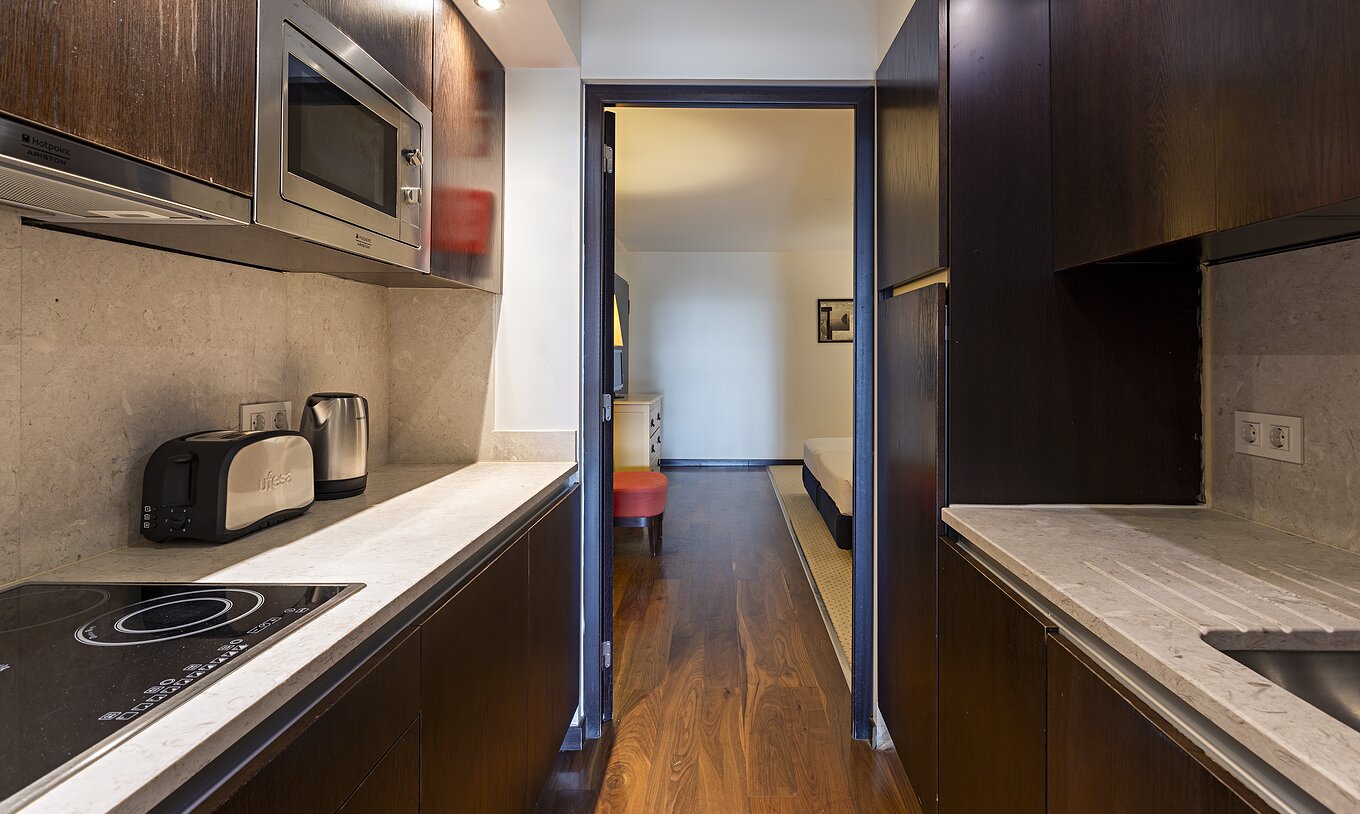 The Cliff Suite T2 at Pestana Alvor Praia has a fully equipped kitchen in dark wood and stone, with a stove and a microwave