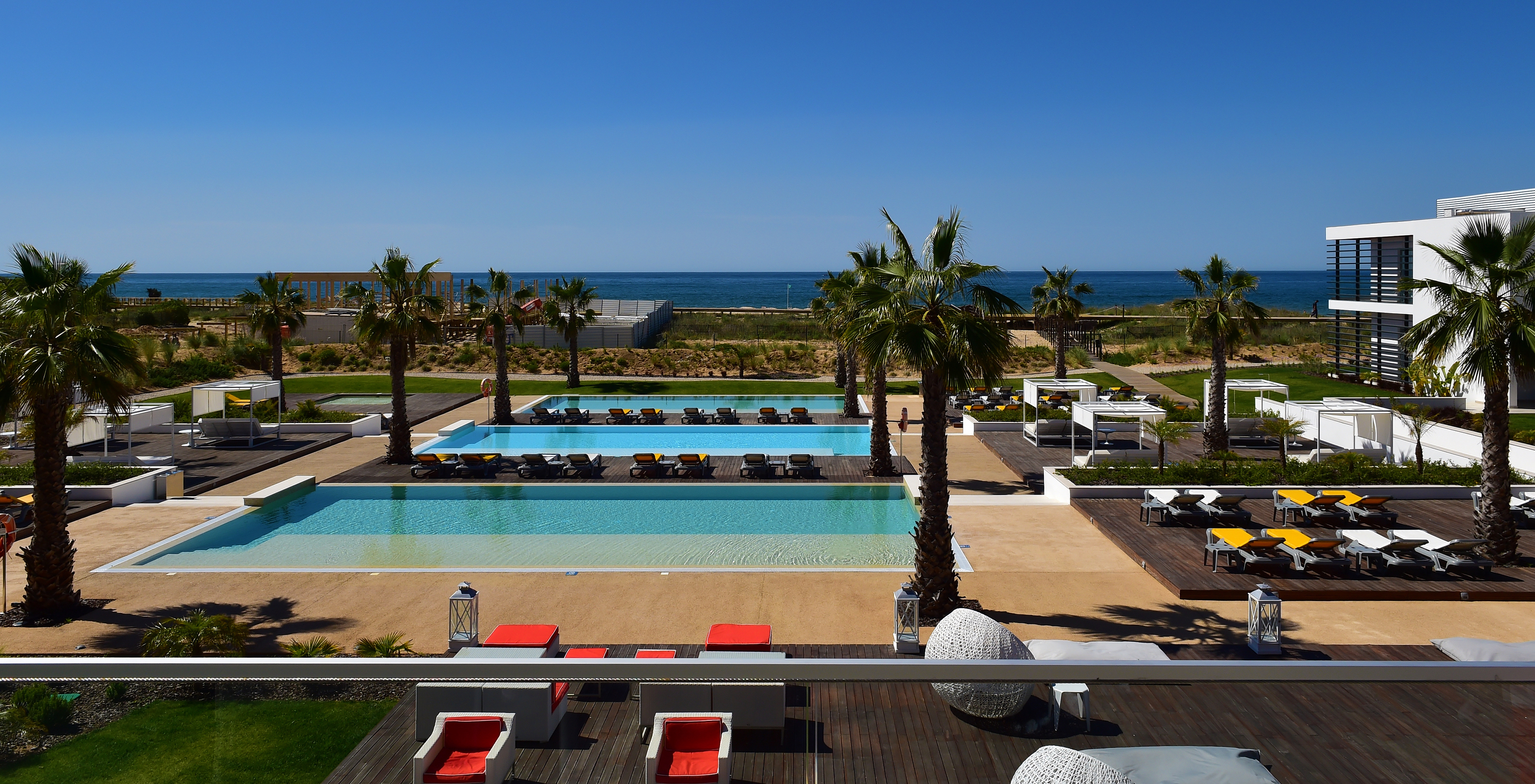 View from the balcony of one of the hotel rooms overlooking the pool area, loungers, and beach