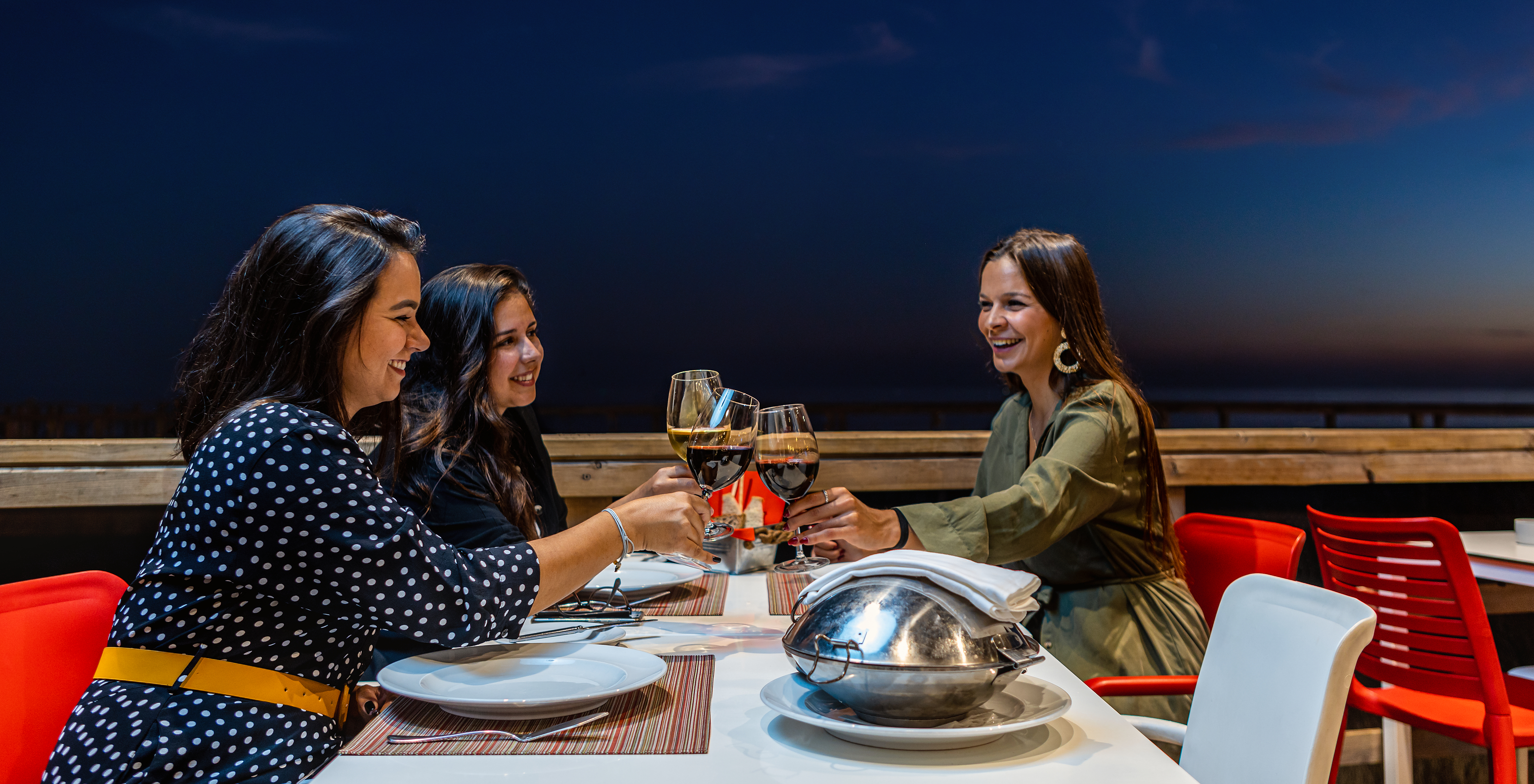 Friends toasting and enjoying dinner and wine on Sea Deck restaurant terrace