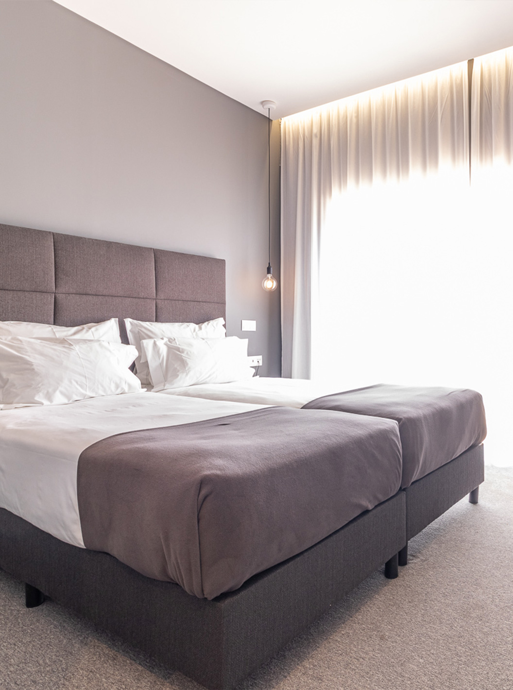 Classic Room at Pestana Gramacho Residences with two beds, grey curtains and table with flowers