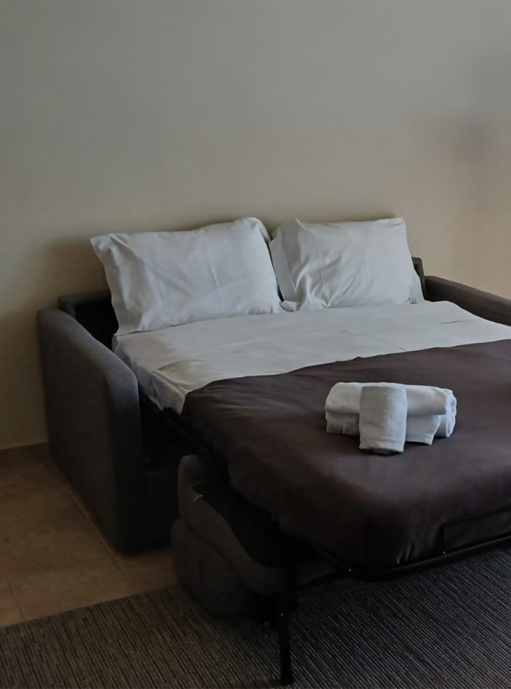 The one-bedroom apartment at Pestana Gramacho has an open sofa bed with white sheets and folded towels